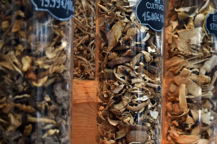 A display of dried mushrooms and herbs in glass containers with price tags. 2