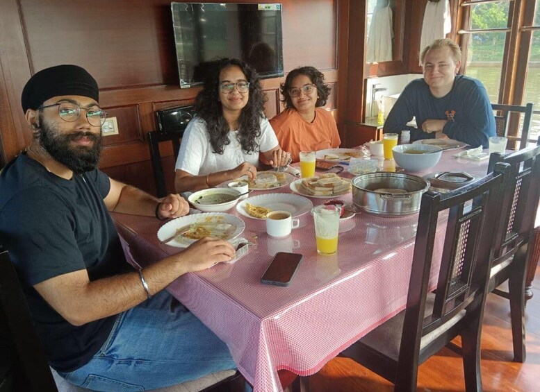 A family dining at a table with plates of food, cups, and a pitcher of juice. 4