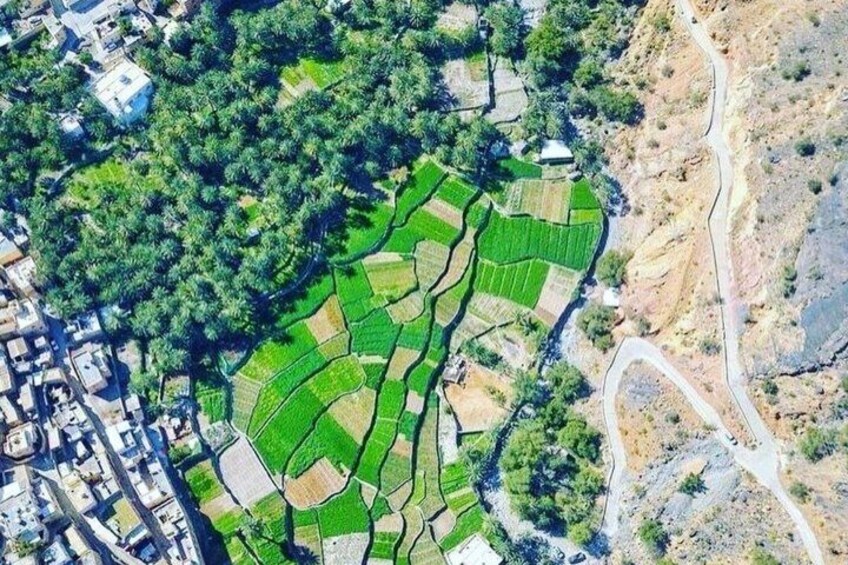 An aerial view of a rural landscape with terraced fields, a winding road, and scattered buildings. 3