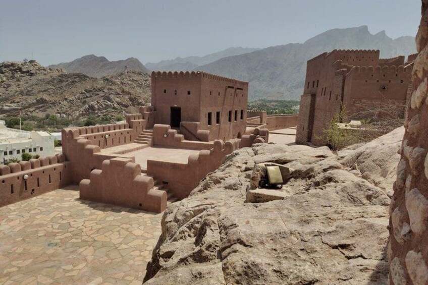 A historical fort with a courtyard, stone walls, and mountainous backdrop. 4