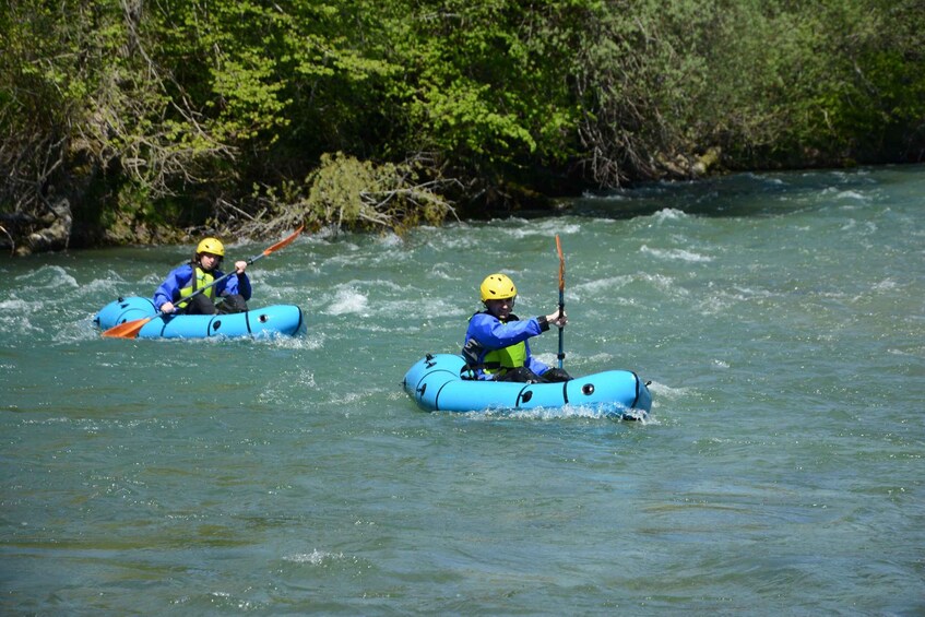 Two people kayaking on a river surrounded by greenery. 3