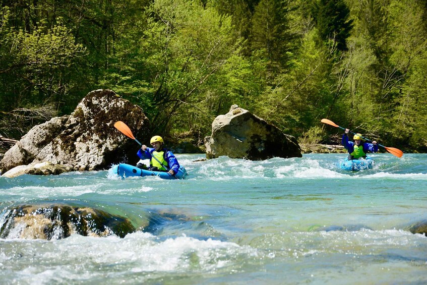 Two kayakers navigating a river with rapids, surrounded by forested banks. 4