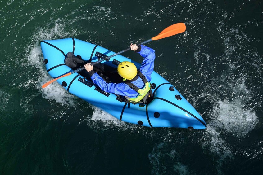A person in a blue kayak with a yellow helmet, paddling on the water. 2