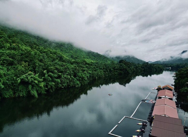A calm river with dense forest on one side and a dock with boats on the other. 1