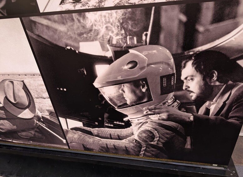 A person in a space suit with a helmet visor, seated in a spacecraft. 3