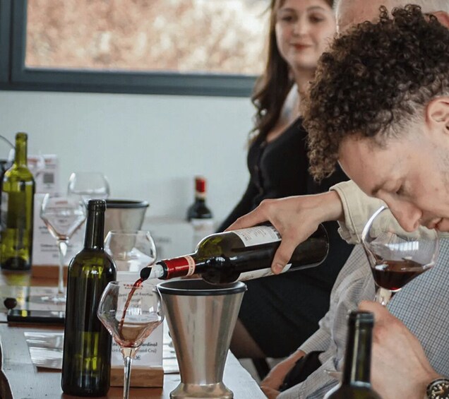 A person pouring wine into a glass. 4