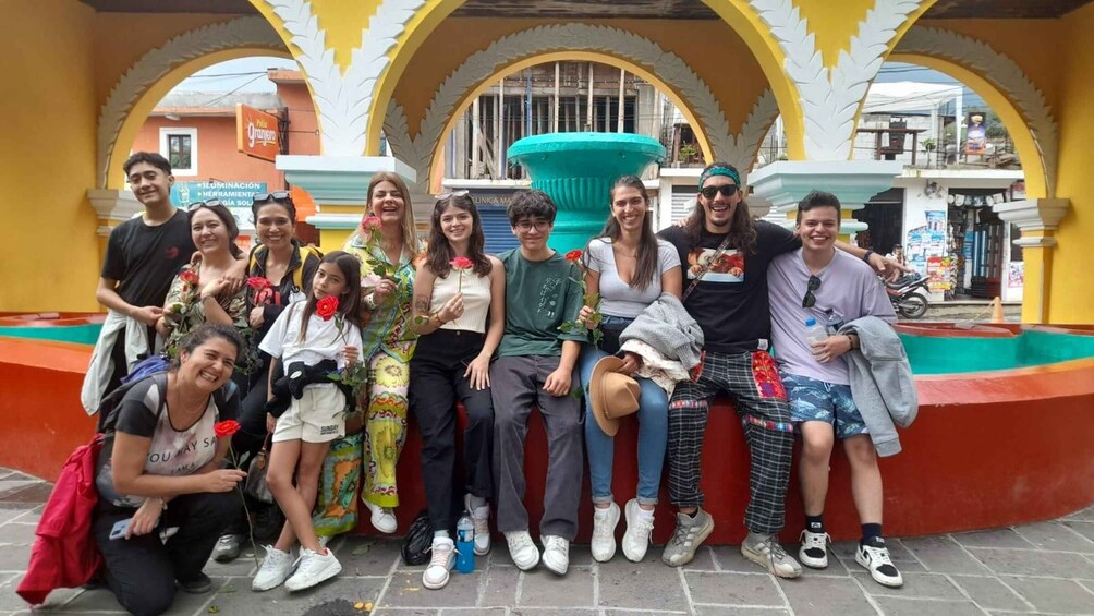 A group of people posing in a colorful courtyard with arches and a fountain. 5