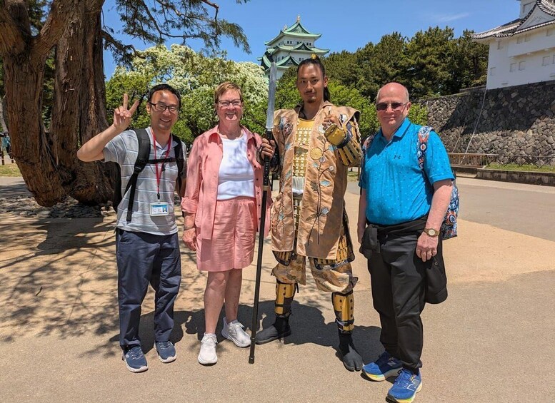 Four people standing in front of a traditional Japanese building with a green roof. 1