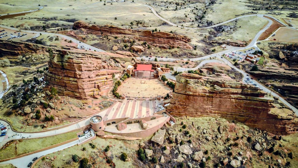 A large amphitheater built into a canyon, surrounded by winding roads and sparse vegetation. 3