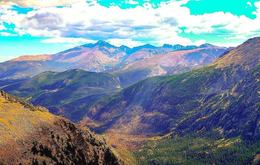 A mountainous landscape with a valley and distant peaks under a partly cloudy sky. 5