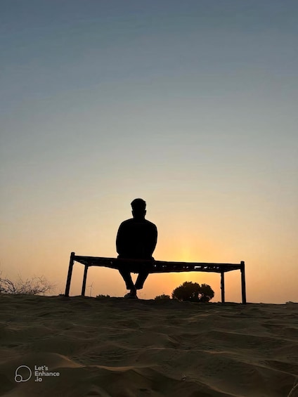 A person sitting on a bench facing the sunset. 1