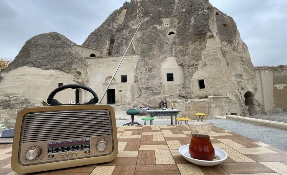 A vintage radio, a plate with a drink, and outdoor seating in front of a rock formation. 3