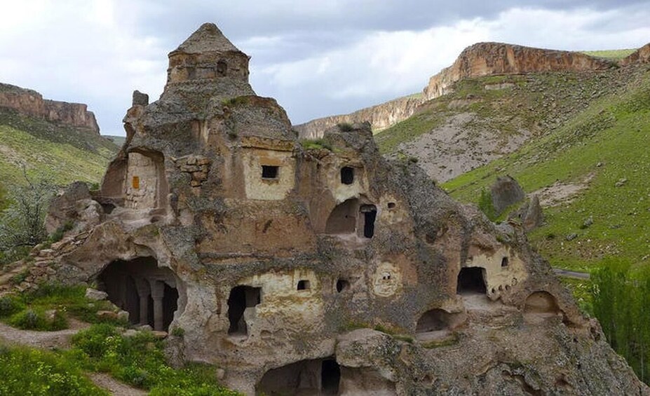 A rock formation with multiple cave dwellings and a small tower. 5