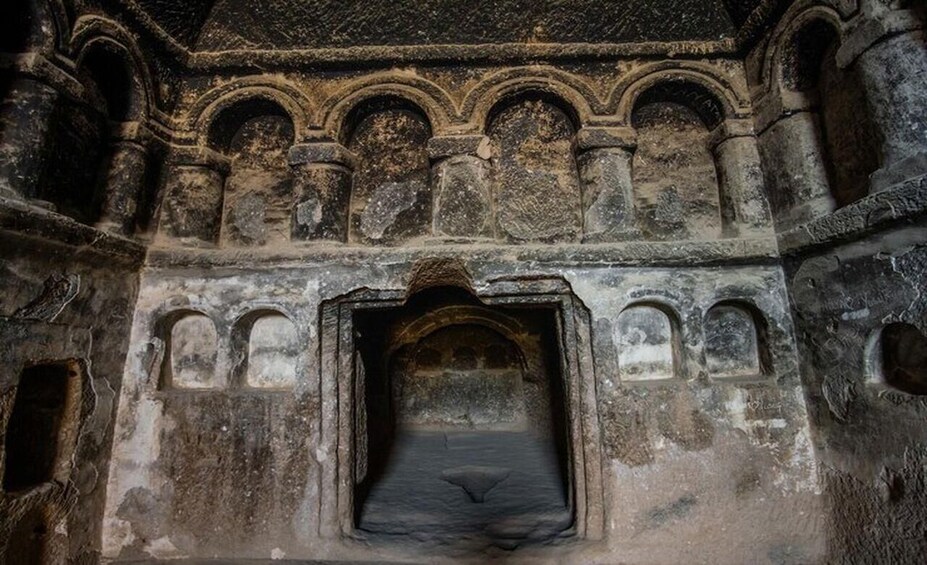 An ancient stone structure with arched doorways and a central passageway. 2