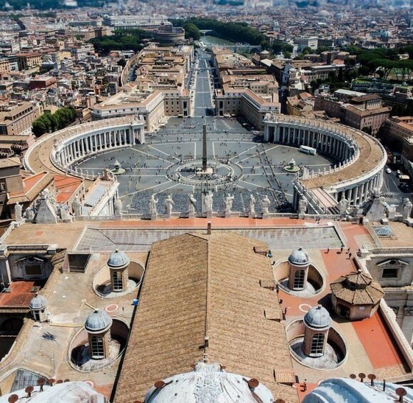 A panoramic view of St. Peter's Square in Vatican City, featuring the iconic St. Peter's Basilica, the obelisk, and the surrounding piazza. 5