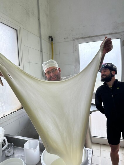 A person holding a long, white, stretchy material in a kitchen setting. 4