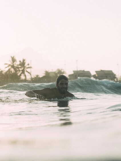 A person surfing on a wave with palm trees and buildings in the background. 4