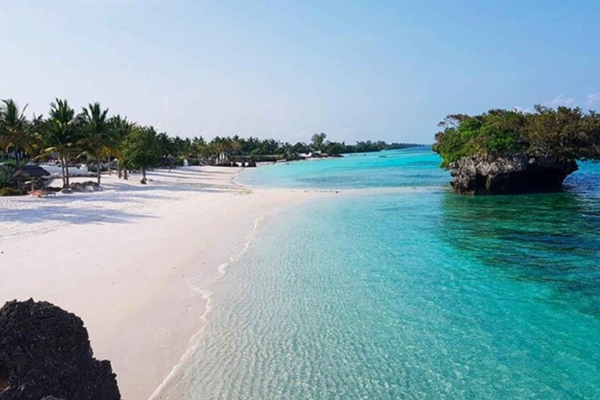 A beach with clear turquoise water, white sand, and palm trees. 4