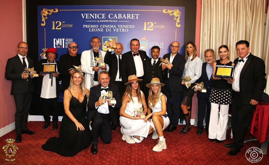 A group of people at an award ceremony with a backdrop that reads 'VENICE CABARET by AVANSPETTACOLO 12th EDITION.' 5