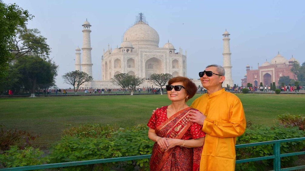 A couple standing in front of the Taj Mahal with the Mughal Gate in the background. 2