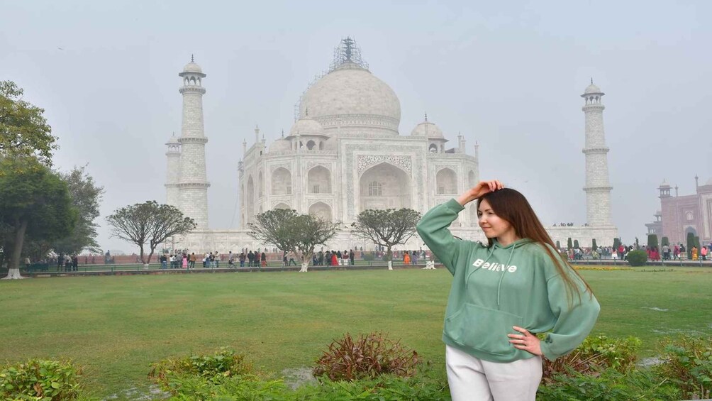 A person standing in front of the Taj Mahal with its four minarets and large dome. 5