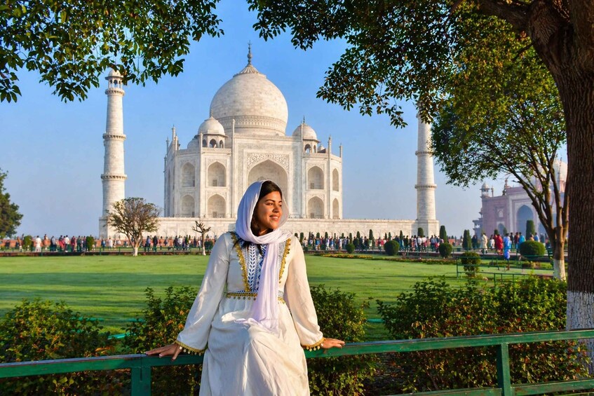 A person in traditional attire standing in front of the Taj Mahal. 3
