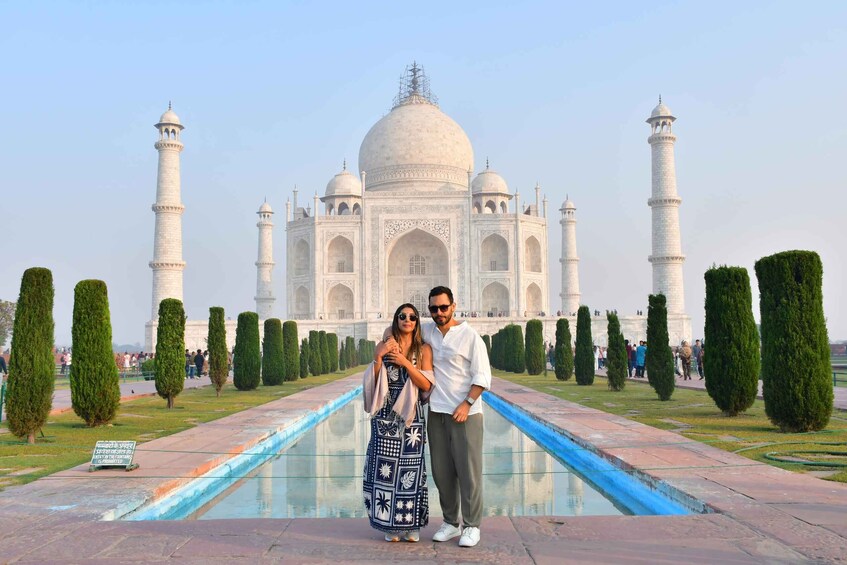 A couple standing in front of the Taj Mahal with its iconic domes and minarets. 4