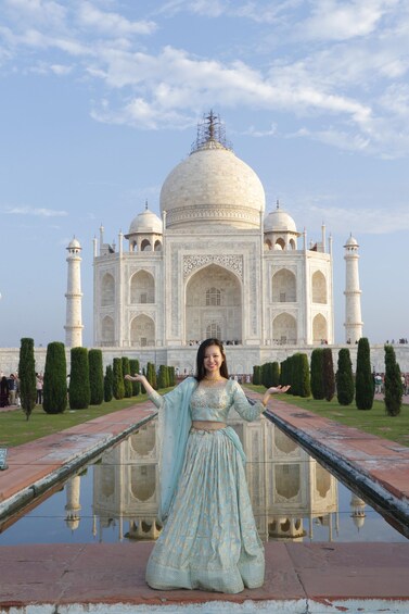 A person in traditional attire standing in front of the Taj Mahal with its reflection in the water. 2