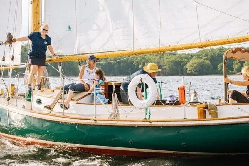 A sailboat with people on board, a lifebuoy, and a calm lake in the background. 5