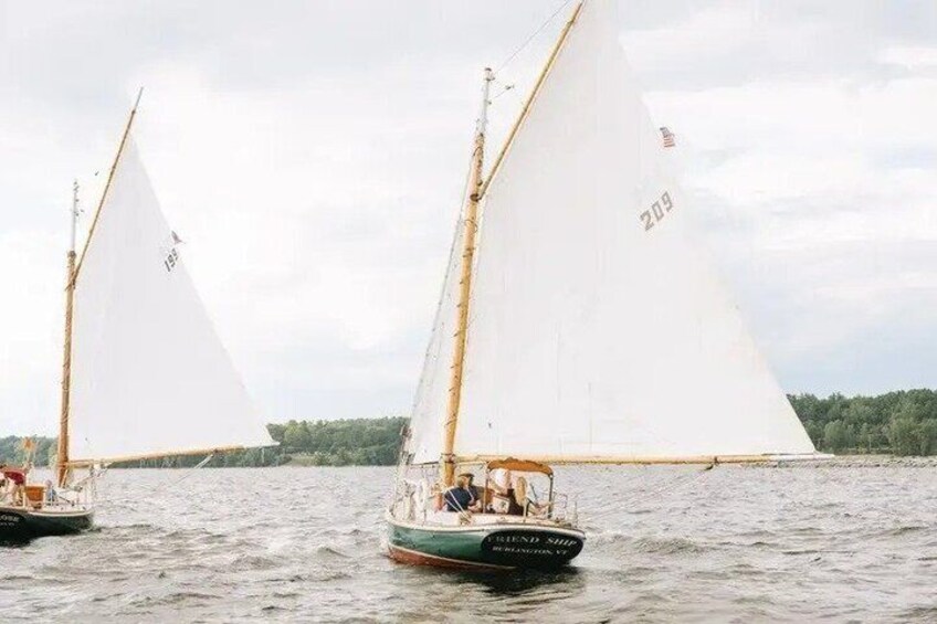 Two sailboats on a body of water with sails unfurled, one with the number 209 visible on its sail. 2