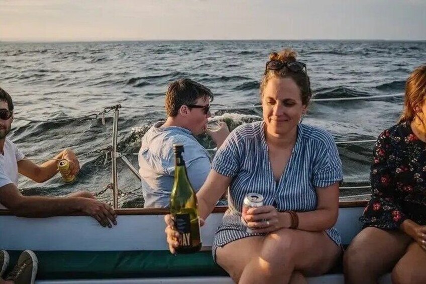 People on a boat with a bottle of wine and a can of beer. 1