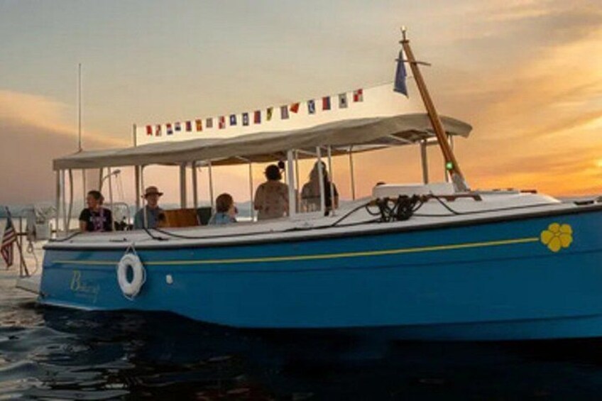 A blue boat with a covered deck and a flag, docked at sunset. 3