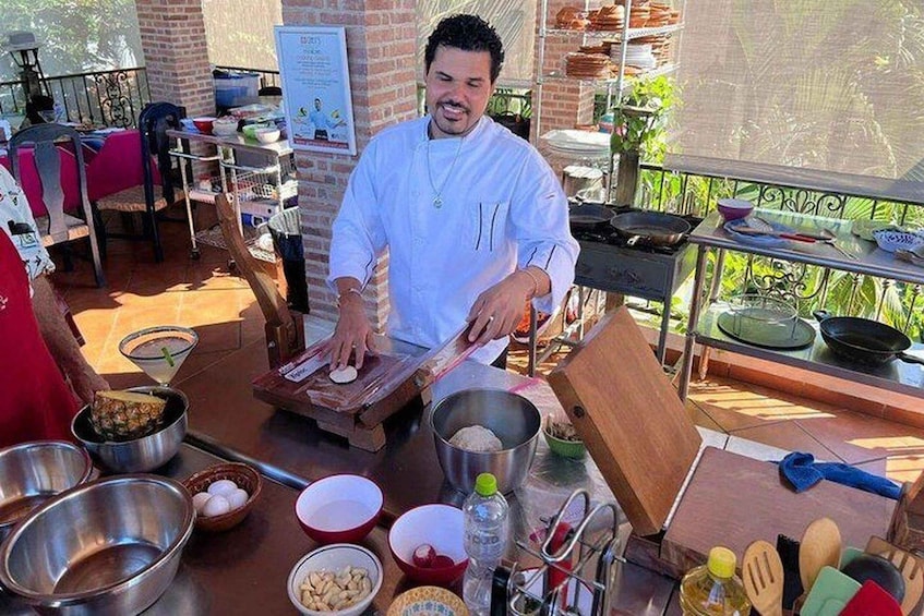 A chef preparing food outdoors with various cooking utensils and ingredients visible. 1