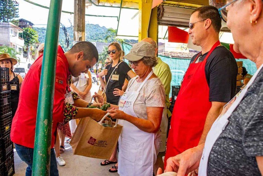People at a street food stall, some wearing aprons, and a woman handing out food. 2