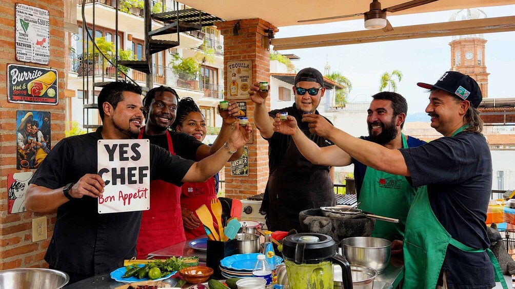 A group of people at a food stall with a sign that reads 'YES CHEF Bon Appetit' and various cooking utensils and ingredients on the counter. 4