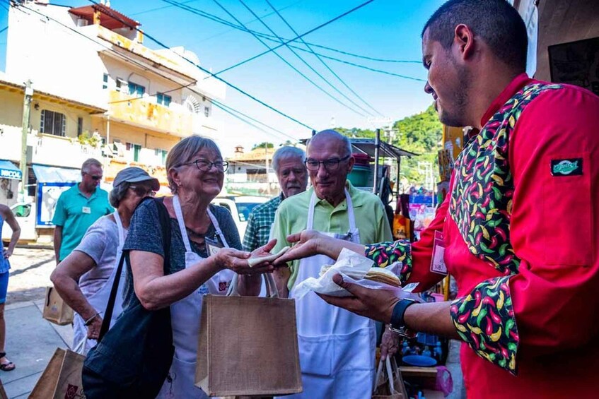 A street vendor in a red shirt serving food to customers. 5