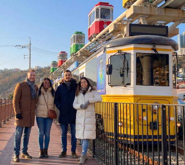 A group of people standing on a bridge with a yellow and white train in the background. 2