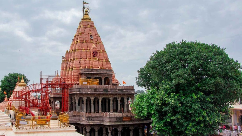 A temple with a large spire, a tree, and scaffolding. 3