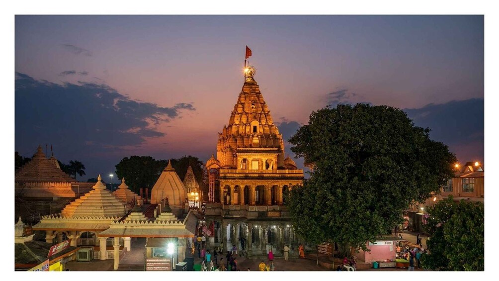 A temple complex at dusk with a prominent central structure and smaller surrounding buildings. 4