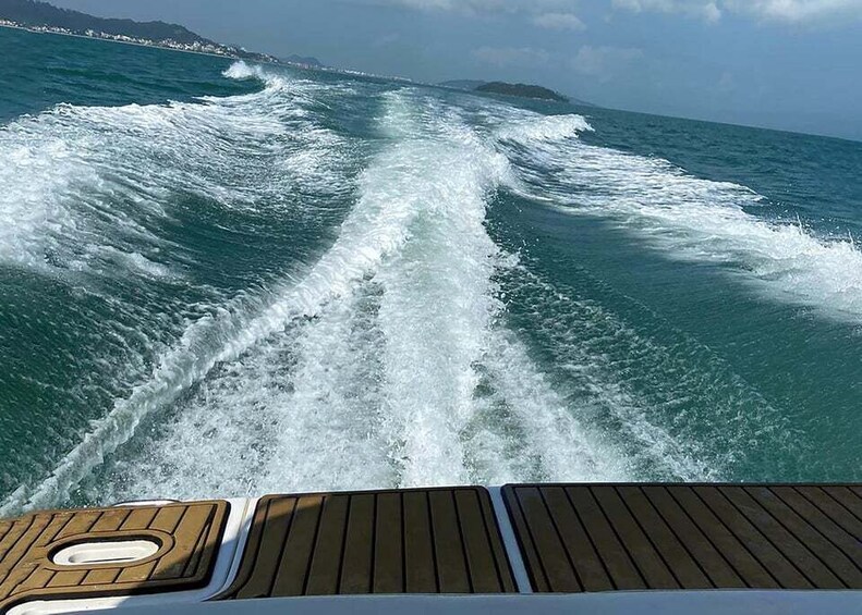 A boat's wake in the ocean with a distant shoreline. 4