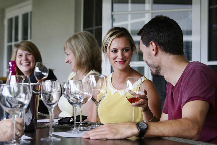 A group of people seated at a table with wine glasses and a pitcher. 2