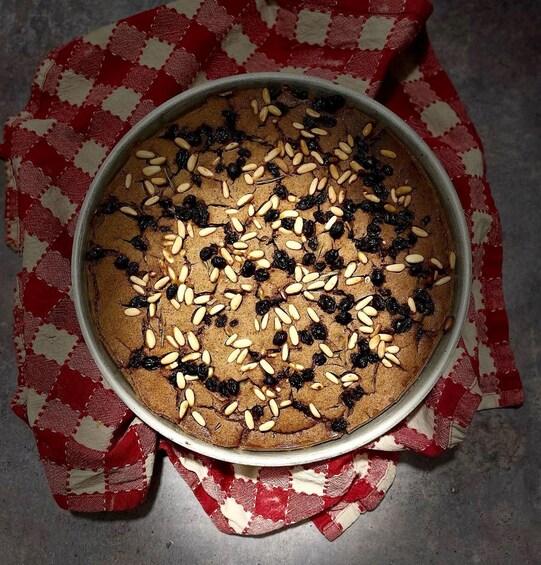 A round cake with raisins and nuts on a metal plate. 1