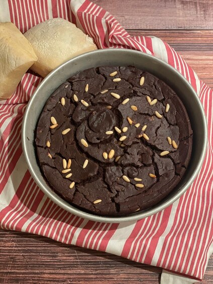 A bowl of chocolate cake with almonds on a striped cloth. 5