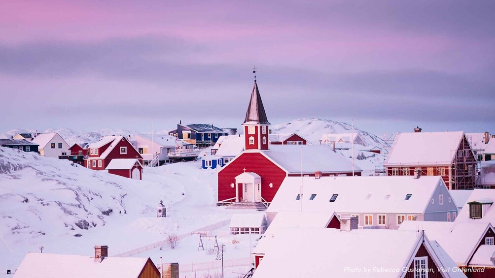 A snowy village with a prominent red church and snow-covered houses. 1