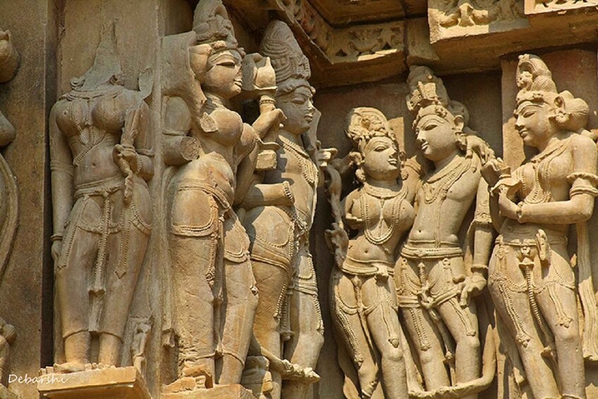 A detailed stone carving of a group of figures in traditional attire, possibly from an ancient temple. 1