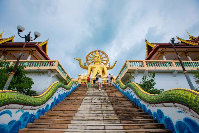 A large golden statue at the top of a staircase with a dragon design on the walls. 4