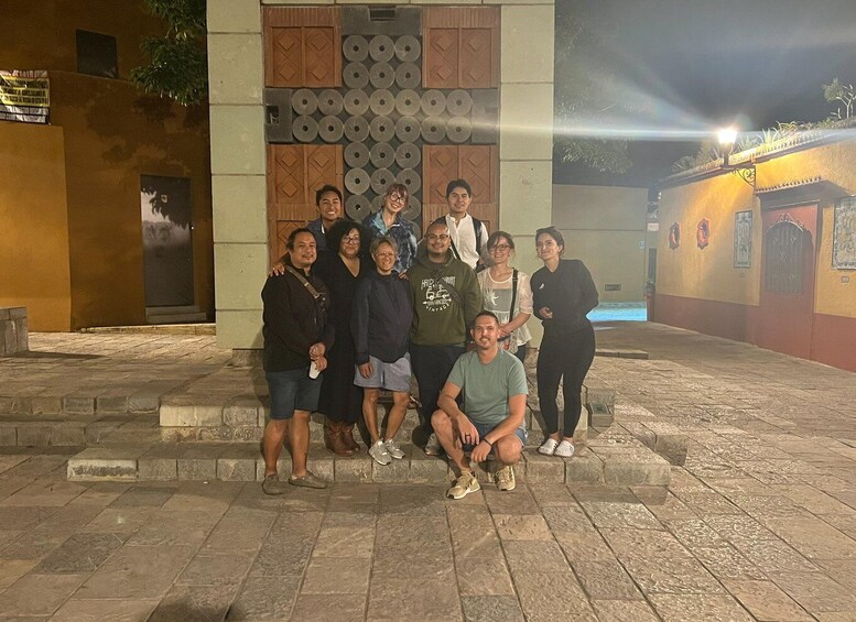 A group of people posing in front of a building with a patterned facade and a door. 1