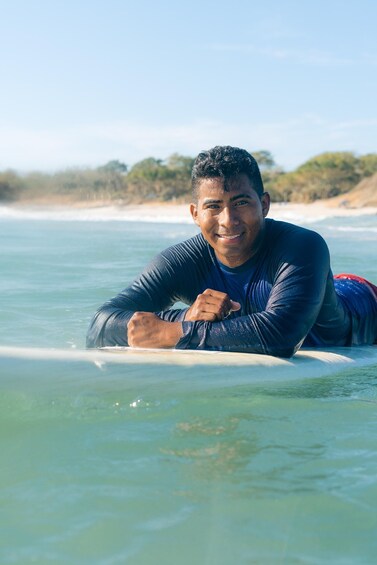 A person lying on a surfboard in the ocean. 4