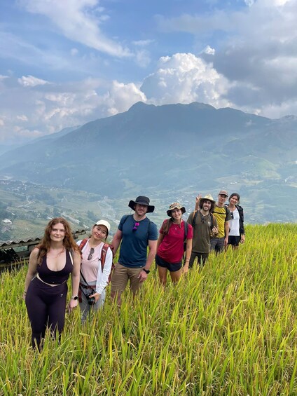 A group of people hiking in a grassy field with mountains in the background. 5