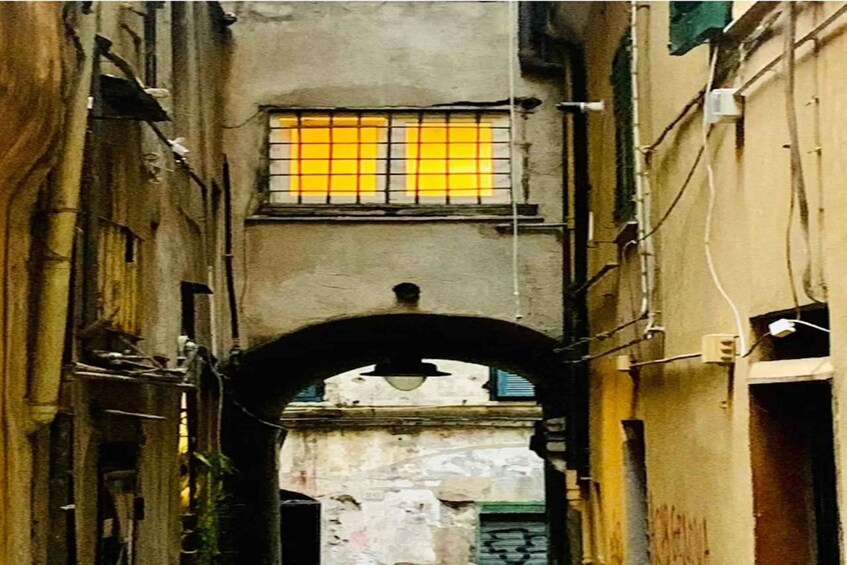A narrow alleyway with an archway, a window with yellow-tinted glass, and a building with visible wear and graffiti. 3